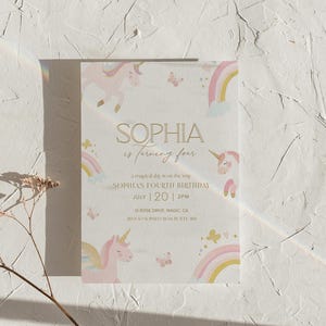 May include: A light-colored invitation card with a unicorn theme. The card features illustrations of unicorns, rainbows, and butterflies in pastel colors. The text reads "SOPHIA is turning four" and details for a birthday party.