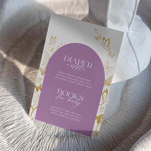 Puede incluir: Invitaci&oacute;n de baby shower morada y blanca con mariposas doradas. El texto dice "Rifa de pa&ntilde;ales" y "Libros para beb&eacute;".