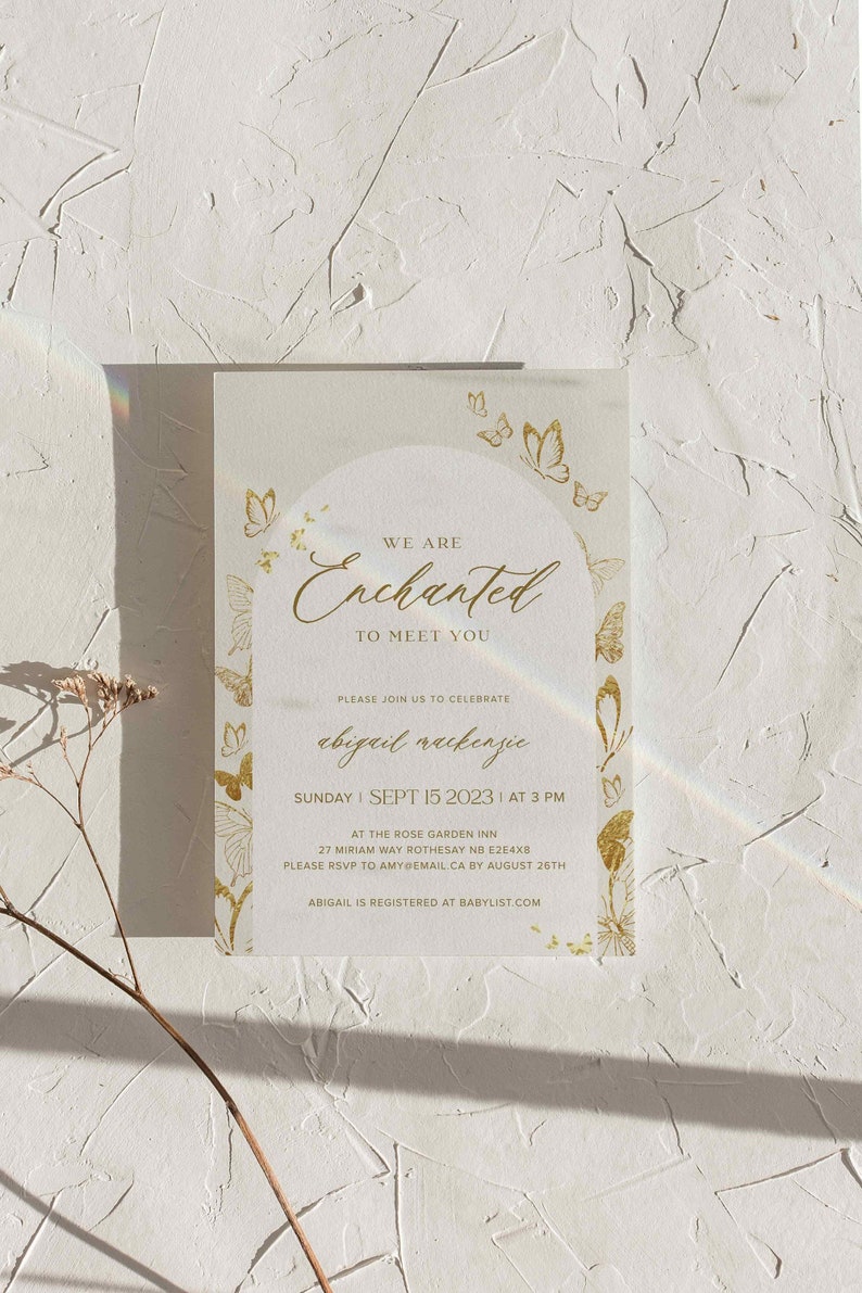 May include: Gold and white baby shower invitation with a butterfly theme. The invitation reads "We are Enchanted to meet you" and includes the name "Abigail Mackenzie" and the date "Sunday, Sept 15, 2023 at 3 PM".