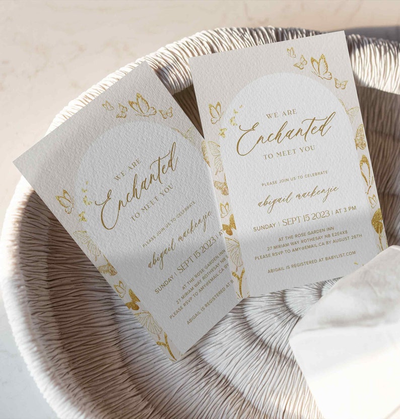 May include: Gold foil baby shower invitation with a butterfly design. The invitation reads "We are Enchanted to meet you" and includes the date, time, and location of the event. The text also says "Please join us to celebrate Abigail Mackenzie".