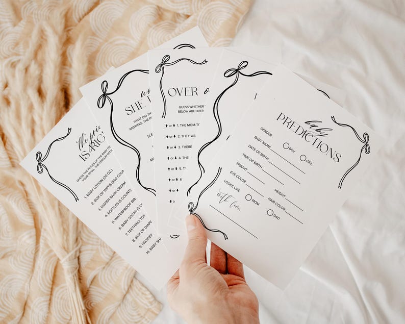 Puede incluir: Un conjunto de tarjetas blancas para juegos de baby shower con texto negro y dise&ntilde;os de lazo decorativos. Las tarjetas incluyen juegos como "El precio es correcto" y "Predicciones" con secciones para rellenar.