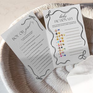 Puede incluir: Dos tarjetas blancas para un juego de baby shower. Una tarjeta dice "&iquest;Ni&ntilde;o o ni&ntilde;a?" con una lista de preguntas. La otra tarjeta dice "Baby Pictionary" con pistas de emoji. Ambas tarjetas tienen bordes negros decorativos.