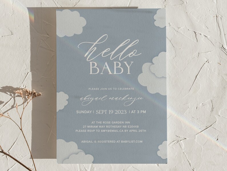 K&ouml;nnte beinhalten: Eine blaue Babyparty-Einladung mit wei&szlig;en Wolken und dem Text "hello baby" und "Please join us to celebrate abigail mackinju". Die Einladung enth&auml;lt Datum, Uhrzeit, Ort und RSVP-Informationen.