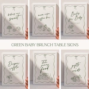 May include: A collection of six white framed signs with green text and illustrations. The signs read: "babies are sweet", "mom-osa coffee bar", "Books for Baby", "Diaper raffle", "enjoy the yummy food", and "gifts & cards". The words "GREEN BABY BRUNCH TABLE SIGNS" are at the bottom.