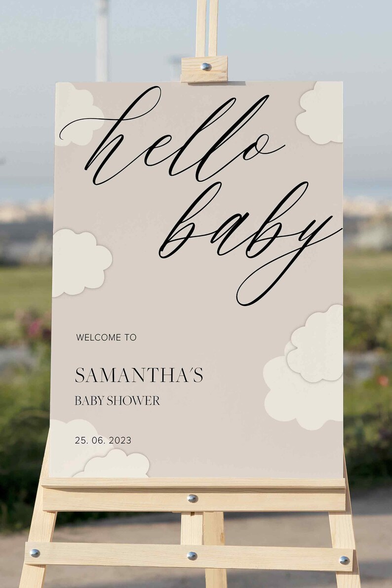 May include: A welcome sign for a baby shower with the text "hello baby" in a cursive font. The sign is beige with white clouds and the text "Welcome to Samantha's Baby Shower 25.06.2023".