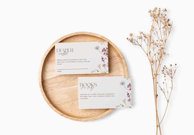May include: Two white cards with floral designs and text. The top card says "Diaper Raffle" and asks guests to bring a pack of nappies for a chance to win a prize. The bottom card says "Books for Baby" and asks guests to bring a book instead of a card.