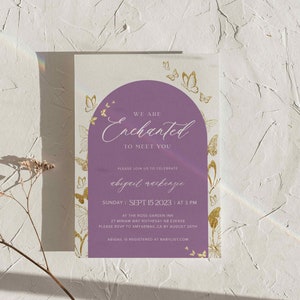 Puede incluir: Invitaci&oacute;n a la fiesta de bienvenida al beb&eacute; de color morado y dorado con tem&aacute;tica de mariposas. La invitaci&oacute;n dice "We are Enchanted to meet you" e incluye el nombre del beb&eacute;, la fecha, la hora y el lugar. Tambi&eacute;n se incluye informaci&oacute;n sobre la confirmaci&oacute;n de asistencia.