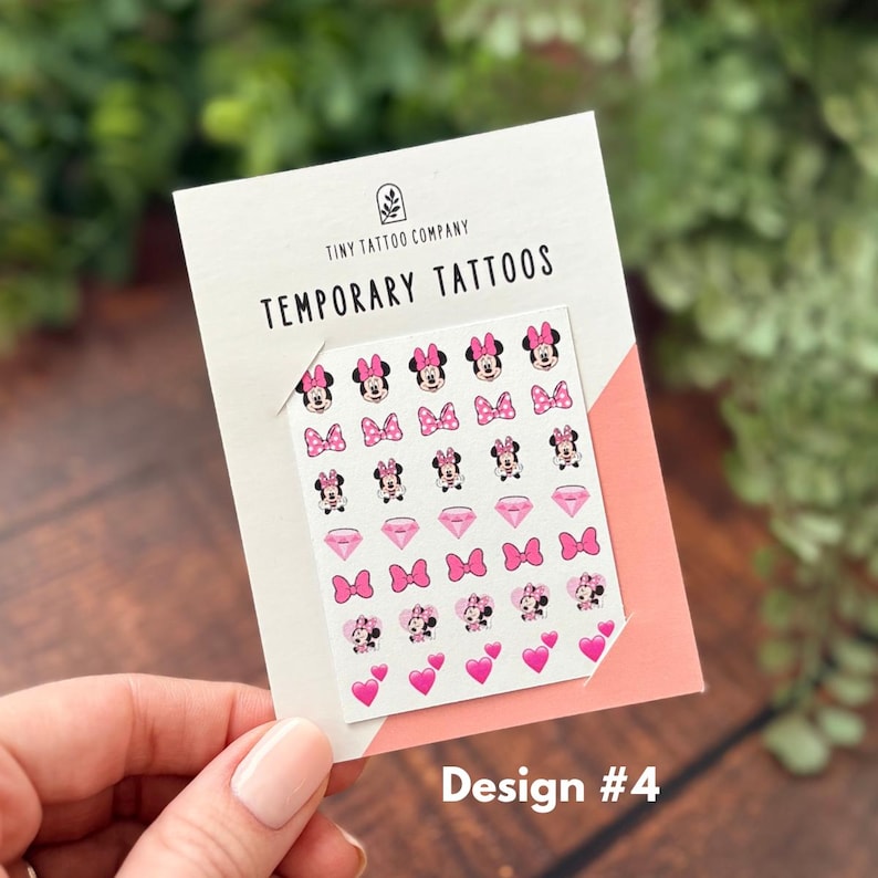 May include: A sheet of temporary tattoos featuring small illustrations of Minnie Mouse, pink bows, diamonds, and hearts on a white backing card labeled Tiny Tattoo Company Temporary Tattoos with the text Design #4 printed at the bottom corner.