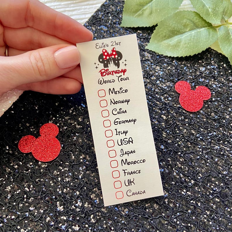 May include: A rectangular white card featuring the text Ellie's 21st Birthday World Tour with a Minnie Mouse icon. Below are checkboxes next to a list of countries including Mexico, Norway, China, Germany, Italy, USA, Japan, Morocco, France, UK, and Canada.