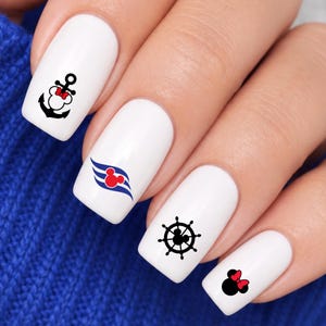 May include: White nail polish base featuring four distinct nautical-themed decals: a black anchor with a red bow, a blue wave design with a red circular icon, a black ship's wheel with a central circular icon, and a black mouse head with a red bow.