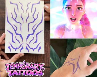 Puede incluir: Una hoja de tatuajes temporales de color morado con patrones dentados similares a rayos. El diseño incluye múltiples formas individuales que se pueden aplicar sobre la piel, como se muestra con la marca morada en una mano.