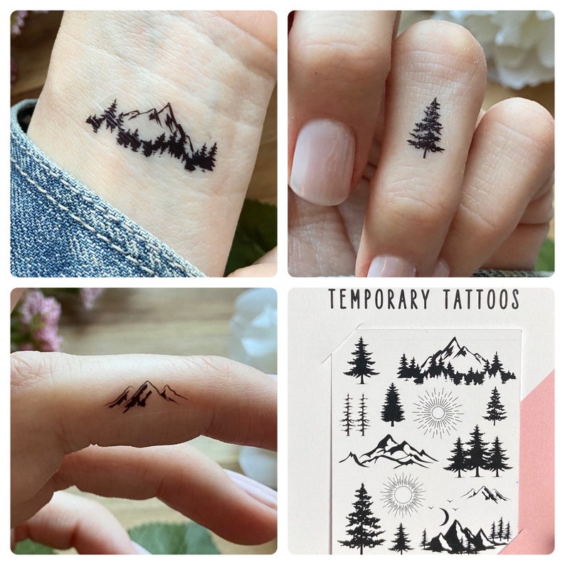 May include: A collection of temporary tattoos featuring mountain and tree designs. The tattoos are black and applied to skin, showcasing the designs on a wrist and fingers. The sheet of tattoos includes various mountain and forest scenes.