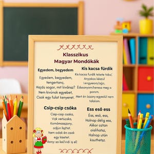 May include: A framed sign with Hungarian nursery rhymes and a cartoon illustration. The sign is surrounded by colorful pencils, a small house-shaped pencil holder, and a green pencil cup. A chalkboard and alphabet letters are in the background.
