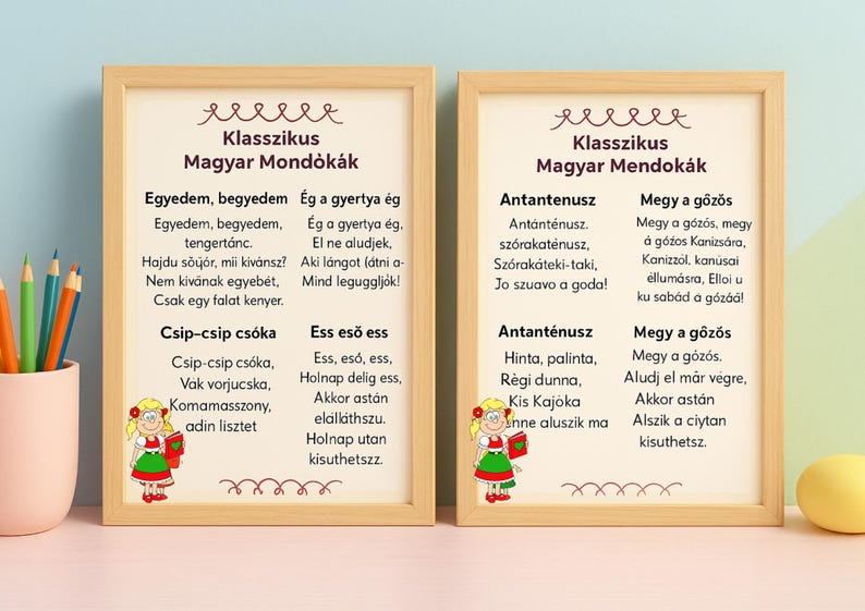 May include: Two framed prints with Hungarian nursery rhymes. The prints have a light wood frame and feature text in a decorative font. Each print has a cartoon illustration of a girl in a traditional outfit.