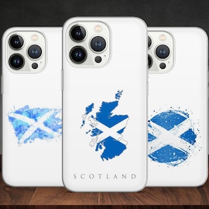 Könnte beinhalten: Drei weiße iPhone-Hüllen mit verschiedenen Designs, die die schottische Flagge zeigen. Die erste Hülle hat ein Aquarell-Design der Flagge. Die zweite Hülle hat eine Karte von Schottland mit der Flagge darübergelegt. Die dritte Hülle hat ein kreisförmiges Design der Flagge mit einem Aquarell-Hintergrund. Alle Hüllen haben den Schriftzug "SCOTLAND" aufgedruckt.