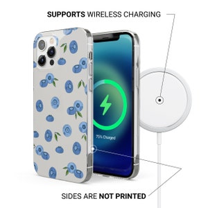 Puede incluir: Una funda transparente para tel&eacute;fono con fondo blanco y un patr&oacute;n de ar&aacute;ndanos azules. La funda se muestra en un tel&eacute;fono con una animaci&oacute;n de carga inal&aacute;mbrica en la pantalla. El tel&eacute;fono se est&aacute; cargando con una plataforma de carga inal&aacute;mbrica.