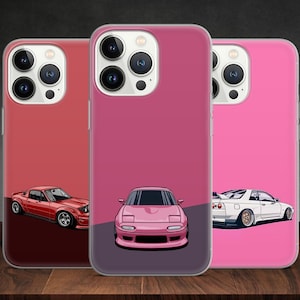 May include: Three phone cases with different coloured backgrounds and car illustrations. The first case has a red background with a red car, the second case has a pink background with a pink car, and the third case has a light pink background with a white car.