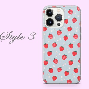 Puede incluir: Una funda transparente para tel&eacute;fono con fondo azul claro y un patr&oacute;n de fresas rojas y flores blancas. La funda est&aacute; dise&ntilde;ada para un tel&eacute;fono con un sistema de c&aacute;mara triple.