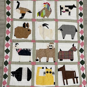 May include: A handmade quilt featuring a patchwork design of farm animals. The quilt showcases a goose, rooster, cow, rabbit, goat, sheep, and other animals. The animals are made from various fabric patterns and colors, set against a white background with a checkered border.
