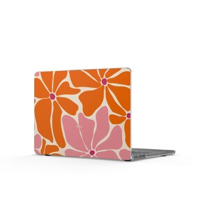 Può includere: Un laptop con una custodia dal design floreale. La custodia presenta grandi fiori arancioni e rosa su uno sfondo bianco sporco. La parola "VALT" è stampata sulla custodia. Il laptop è aperto e lo schermo è visibile.