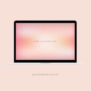 May include: A laptop computer with a pink and orange gradient background on the screen. The text "make yourself proud" is displayed in pink on the screen. The laptop is on a white surface.