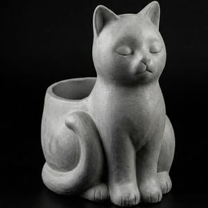May include: A gray cat-shaped planter with closed eyes, a curled tail, and a small opening for plants. The cat is sitting upright, with its paws visible. The planter is made of a solid material.
