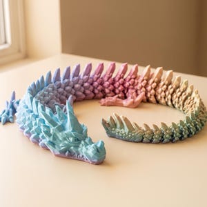 Könnte beinhalten: Eine 3D-gedruckte, bewegliche Drachenfigur mit einem geometrischen, kristallartigen Schuppenmuster. Der Drache zeigt einen mehrfarbigen Farbverlauf, der vom hellen Blau am Kopf bis hin zu Rosa, Orange und Grün entlang des langen Körpers reicht.