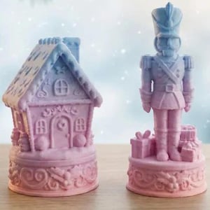 May include: Two-piece Christmas decor set. A pink and blue gingerbread house and a nutcracker soldier figurine. The house has a detailed roof and windows. The soldier stands on a base with gifts. Festive holiday decorations.
