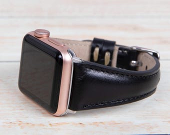 May include: A rose gold Apple Watch with a black leather band. The band has a stitched edge and a buckle closure.