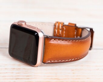 May include: Rose gold smartwatch with a brown leather strap. The strap is stitched with white thread and has a silver buckle. The watch face is black.