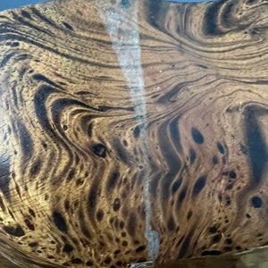 K&ouml;nnte beinhalten: Nahaufnahme einer Holzschale mit einem dunkelbraunen und hellbraunen Marmormuster. Die Schale hat einen wei&szlig;en Riss, der durch die Mitte verl&auml;uft.