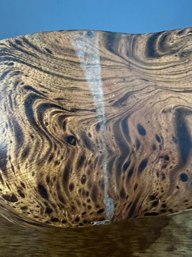 K&ouml;nnte beinhalten: Nahaufnahme einer Holzschale mit einem dunkelbraunen und hellbraunen Marmormuster. Die Schale hat einen wei&szlig;en Riss, der durch die Mitte verl&auml;uft.