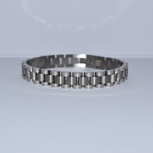 Op de afbeelding: Een zilveren metalen armband met een schakellinkontwerp.