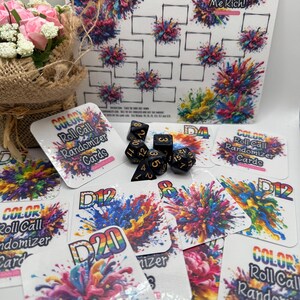 May include: A tabletop game set featuring a white game board with colorful abstract art and the text "COLOR Me Rich!". Includes dice and cards with the text "COLOR Roll Call Randomizer Cards" and "D20". A bouquet of pink flowers is in the background.