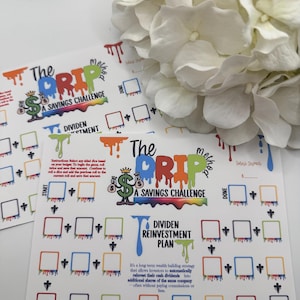 May include: White rectangular savings challenge cards with colorful text and graphics. The cards feature the text "The Drip A Savings Challenge" and "Dividend Reinvestment Plan". Each card has multiple boxes for tracking savings.
