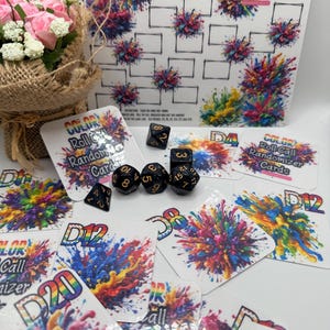 May include: A collection of colorful gaming accessories, including dice and cards. The cards feature vibrant abstract art and text that reads "COLOR Roll Call Randomizer Cards". A white board with a grid and the text "COLOR Me Rich!" is also present.