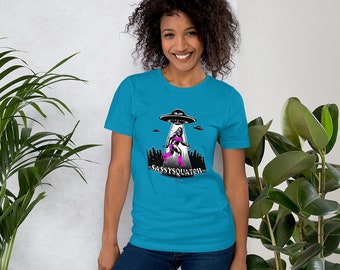 Original Sassysquatch Unisex T-shirt de Scarpace, Female Bigfoot Sasquatch in the Woods with UFO's, Believe, Pink Bikini and Boots