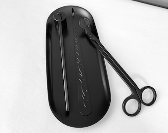Könnte beinhalten: Schwarzes Kerzenlöscher- und Docht-Schneide-Set auf einem schwarzen Tablett. Der Löscher hat ein dekoratives Design.