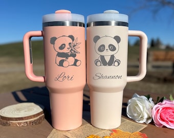 Op de afbeelding: Twee gepersonaliseerde reistassen met een pandabeerontwerp. De beker links is roze en zegt "Lori" en de beker rechts is wit en zegt "Shannon".