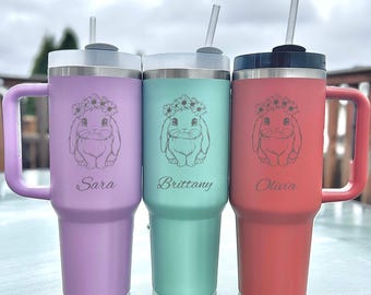 May include: Three personalized tumblers in lavender, teal, and coral, each with a handle, straw, and a floral bunny design. The names "Sara", "Brittany", and "Olivia" are engraved below the bunny illustrations.