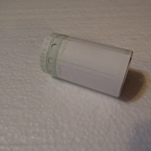 May include: A white roll of thermal paper with a green printed border and the word "Thermal" printed on the side.