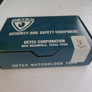 May include: A blue box with white text that reads "DETEX SECURITY AND SAFETY EQUIPMENT DETEX CORPORATION NEW BRAUNFELS, TEXAS 78130 DETEX WATCHCLOCK TAPE" and a white circle with the text "DETEX QUALITY" in the top right corner.