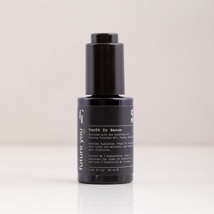 May include: A black glass bottle with a dropper top containing a serum called "Youth In Serum" by the brand "future you PSS". The bottle is labeled with the text "Enriched with Sea buckthorn oil, Evening Primrose Oil, Tamanu Seed Oil" and "Provides hydration, helps to smooth fine lines and wrinkles, and support skin elasticity."