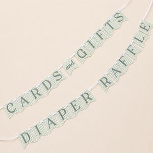 K&ouml;nnte beinhalten: Zwei hellgr&uuml;ne Vichy-Girlanden mit wei&szlig;er Schnur. Auf der einen Girlande steht "CARDS and GIFTS", auf der anderen "DIAPER RAFFLE". Die Buchstaben sind dunkelgr&uuml;n.