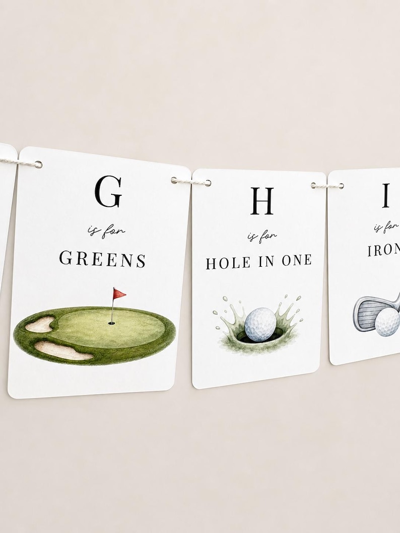 May include: A white paper banner featuring golf-themed alphabet cards. One card shows a green with a red flag and the text G is for GREENS. Another card displays a golf ball splashing into a hole with the text H is for HOLE IN ONE.