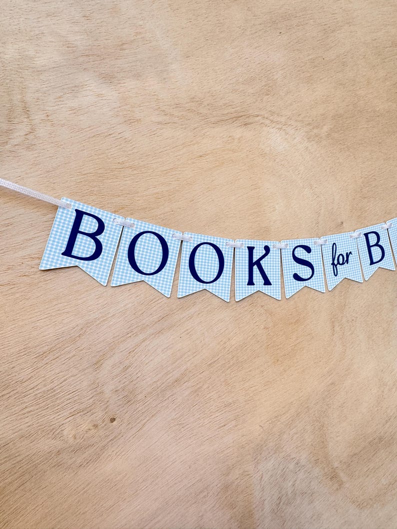K&ouml;nnte beinhalten: Ein Banner mit blau-wei&szlig; karierten Wimpeln schreibt "BOOKS for B". Die Buchstaben sind marineblau. Das Banner ist auf einem wei&szlig;en Band aufgereiht, und der Hintergrund ist eine hellbraune Holzoberfl&auml;che.
