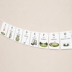 May include: A decorative banner featuring eight white rectangular cards strung together, each displaying a letter from A to H with golf-themed illustrations and text including A is for Ace, B is for Birdie, C is for Caddie, D is for Driver, E is for Eagle, F is for Fairway, G is for Greens, and H is for Hole in One.