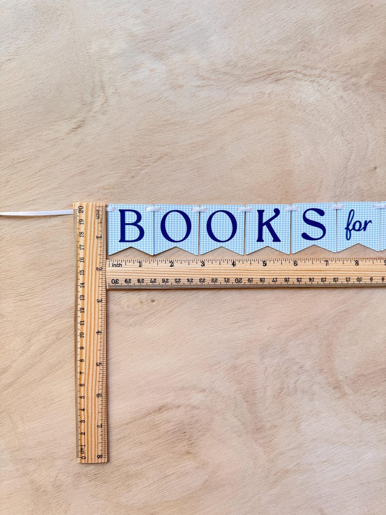 K&ouml;nnte beinhalten: Ein Banner mit der Aufschrift "BOOKS for" in marineblauen Buchstaben. Das Banner besteht aus blau-wei&szlig; karierten Flaggen. Ein Holzlineal liegt daneben und misst in Zoll. Das Lineal ist etwa 50 cm lang.