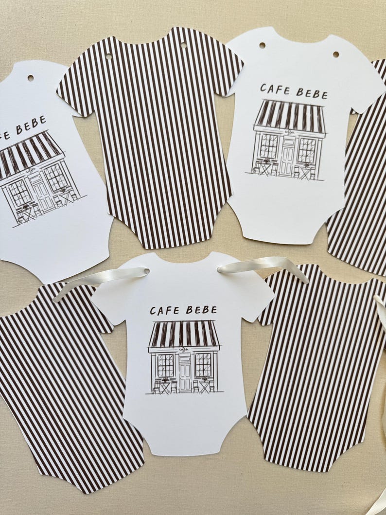 May include: White baby bodysuit-shaped tags with black and white striped patterns and the text "CAFE BEBE". Some tags feature a cafe illustration. Each tag has a hole for ribbon.