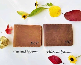 May include: Two leather wallets in different shades of brown. The wallet on the left is labeled "Caramel Brown" and has the initials "KCP" embossed on it. The wallet on the right is labeled "Walnut Brown" and has the initials "LBJ" embossed on it.